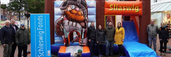 Gruppenfoto vor der neuen Wikingerhüpfburg am Capitolplatz: Stefan Wesemann (IHK), Helge Schütze (Stadtmarketing), Hanns-Peter Arp (Zukunftsbeirat Schleswig Fonds), Björn und Marta Danczak (M. B. D. Hüpfburgenvermietung), Torge Nehls (Helios Klinik), Josephin Schäfer (Stadt Schleswig), Thomas Forck (Schuhgeschäft Forck, IGL) und Rowena Sandmeier (Stadt Schleswig).