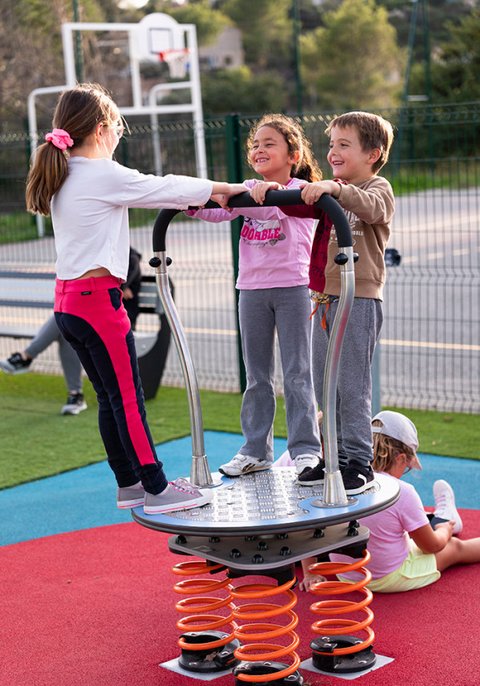 Spielplatzgerät Rodeoboard mit drei spielenden Kindern