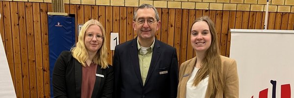 Anna Puhlmann, Auszubildende zur Erzieherin in praxisintegrierter Form aus der Kita Bildungsbox und Norbert Krüger sowie Julia Sell aus dem Fachdienst Personal hinter einem Messestand