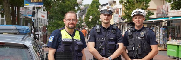 Ein Mitarbeiter des Kommunalen Ordnungsdienstes mit zwei Polizisten neben einem Polizeiauto im Stadtweg in Schleswig.