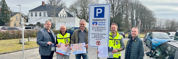 Zeitweise Freigabe der VR-Parkplätze: H. Schütze (Stadtmarketing), D. Jürgensen (FD Tiefbau), M. Möller (Vorstand VR-Bank Nord), T. Krüger (FD-Leiter Tiefbau) und R. Gottschalk (VR Bank Nord) vor einem Schild mit Öffnungszeiten