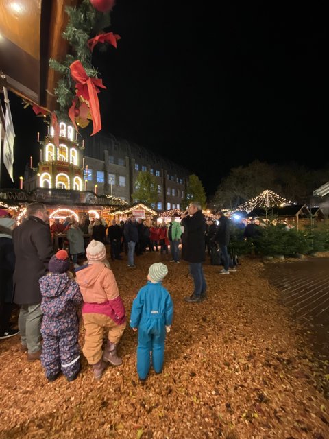 Kinder von hinten vor der Weihnachtspyramide des Schleswiger Weihnachtsmarktes