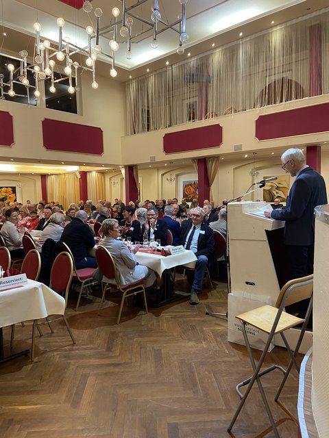 Joachim Rossi vom Schleswiger Bürgerverein blickt in einen Saal mit vielen Menschen