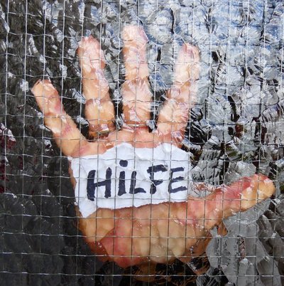 Hand hinter Milchglasscheibe mit schwarzem Text Hilfe