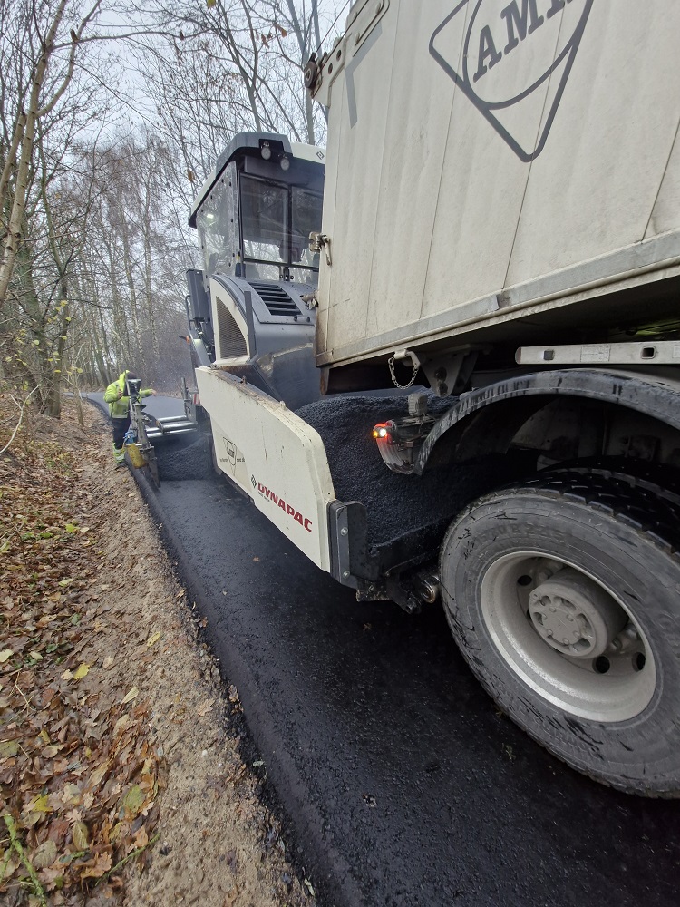 KBT 3. BA Asphalteinbau durch den Fertiger. Der Fertiger bringt den Asphalt auf die Trasse auf. Es riecht stark nach Teer und ist sehr warm.