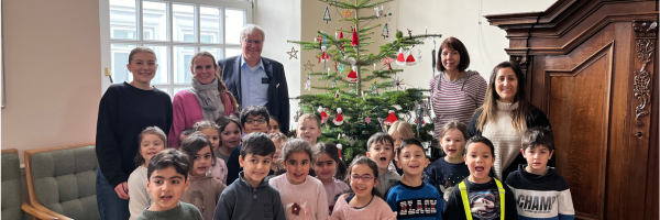 Gruppenfoto der Kinder mit Stephan Dose vor dem Weihnachtsbaum